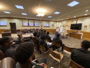 Early Outreach Initiative students sitting in a conference room with Dean Andy speaks in front of them.