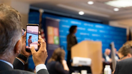 Man taking a picture of BW75 conference panel on his phone