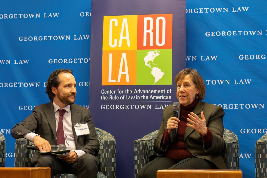 Professor Santos and Ambassador Lisa Kubiske talking at the conference in front of the CAROLA banner.