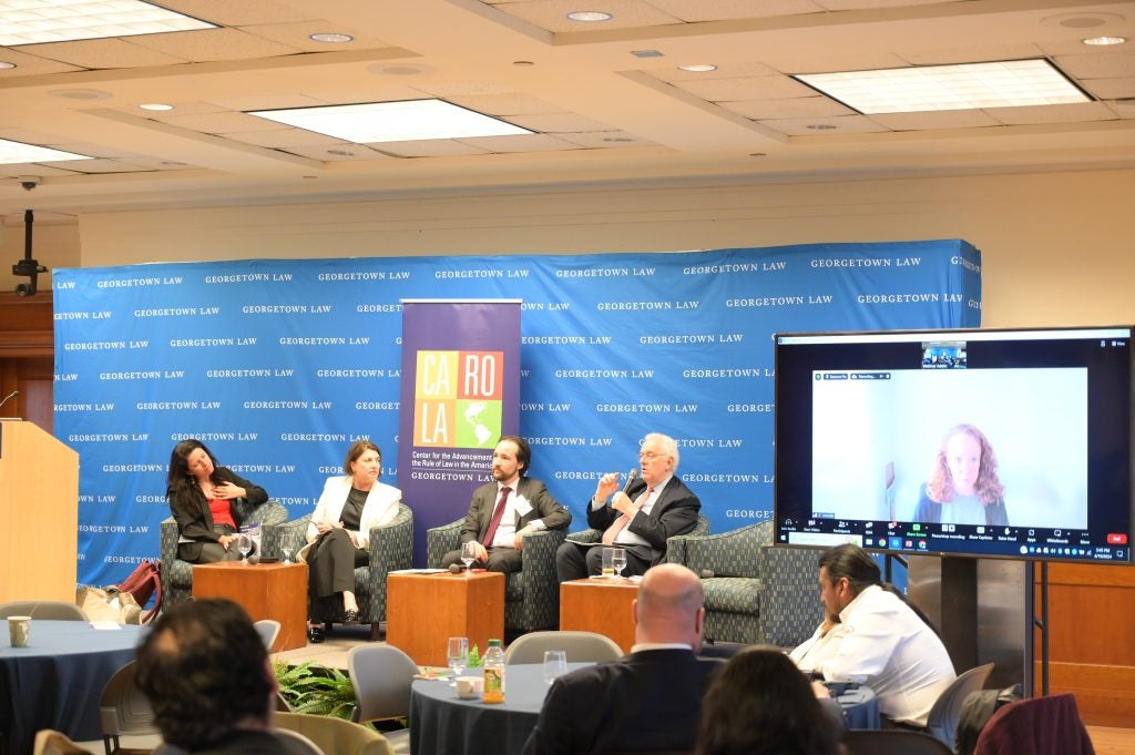 A far away look at the panel at the LAPEG conference showing Moderator Alvaro Santos and presenters Cristina Reis, Ana Maria Ibanez, Jose Antonio Ocampo and, on the screen, Jennifer Harris.