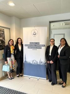 2025 Vis Moot team standing with a Vis Moot banner