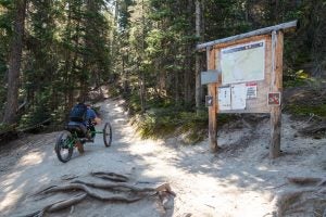 A hiker in a wheelchair takes to a trail in Yellowstone National Park. (Source: Yellowstone National Park, Flickr, https://flic.kr/p/283wvkb)