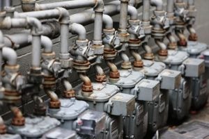 Row of industrial gas meters with intricate piping network.