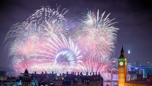 Pink and white fireworks erupt over London at night.