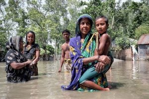 People wading through floodwaters illustrate human vulnerability to climate impacts.