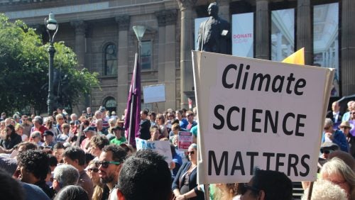 A large crowd gathered for a public demonstration, where a prominent sign reads "CLIMATE SCIENCE MATTERS," highlighting the advocacy for scientific integrity in environmental policy.
