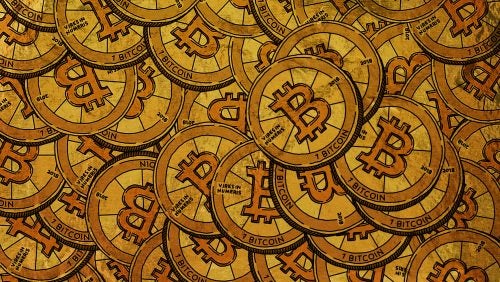 A visual representation of physical BItcoin coins layered to form a background.