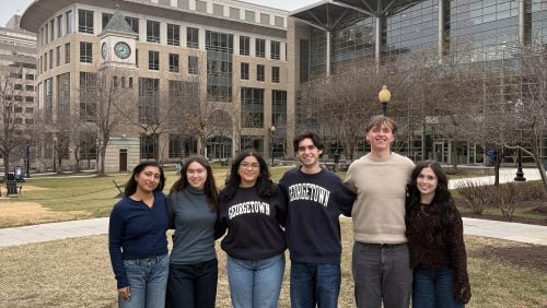 Student interns standing outside near the clocktower green