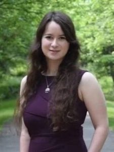 Woman in purple dress in front of green trees