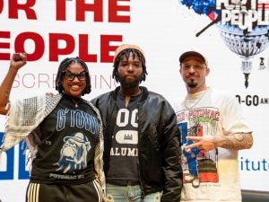Kelsye, Yaddiya, and Sebastian in front of film logo