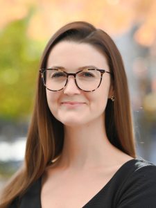 Julia in a black top, glasses, outside