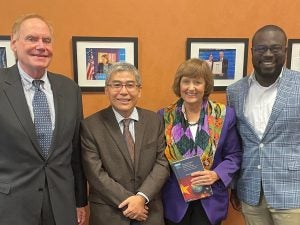 Speakers of the event posing with a copy of the book