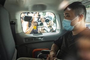 Tong Ying-kit arrives at court while press take photos through the car window.