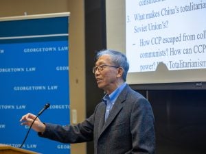 Professor Xu Chenggang speaking behind a podium.