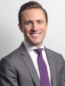 A smiling young man with a purple tie