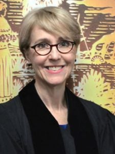 A smiling woman in a judges robe with short hair and glasses