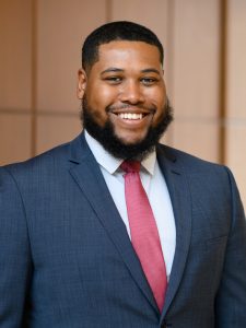 A smiling man with a beard and a pink tie