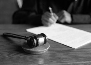 A desk with a gavel on it and a judge writing in black in white