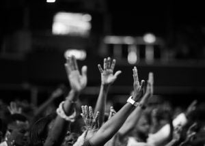 A black and white photo of a number of hands rising out of a crowd