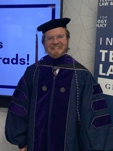 Logan Arkema posing in a graduation cap and gown