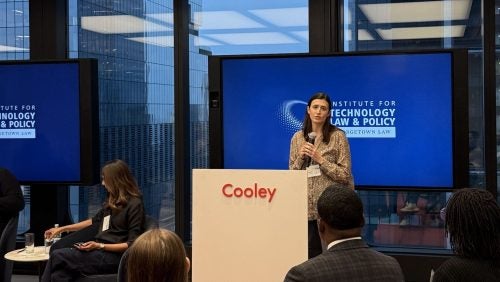 A woman speaks to students at Cooley LLP's office, in front of a Tech Institute sign.