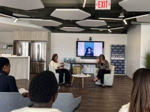 Nicol Turner Lee and Nina-Simone Edwards sit and talk in front of a display of Dr. Lee's book.