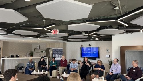 Students and panelists sit around a table and speak together at Noshes with Natalie