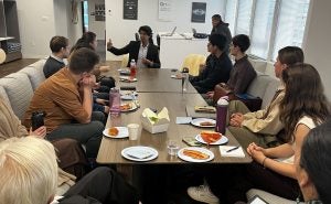 Faiz Thakur speaks to many students, who are sitting around a table