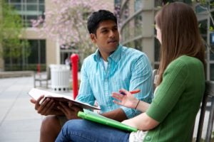 Two students talking on a bench outside Sports and Fitness Center