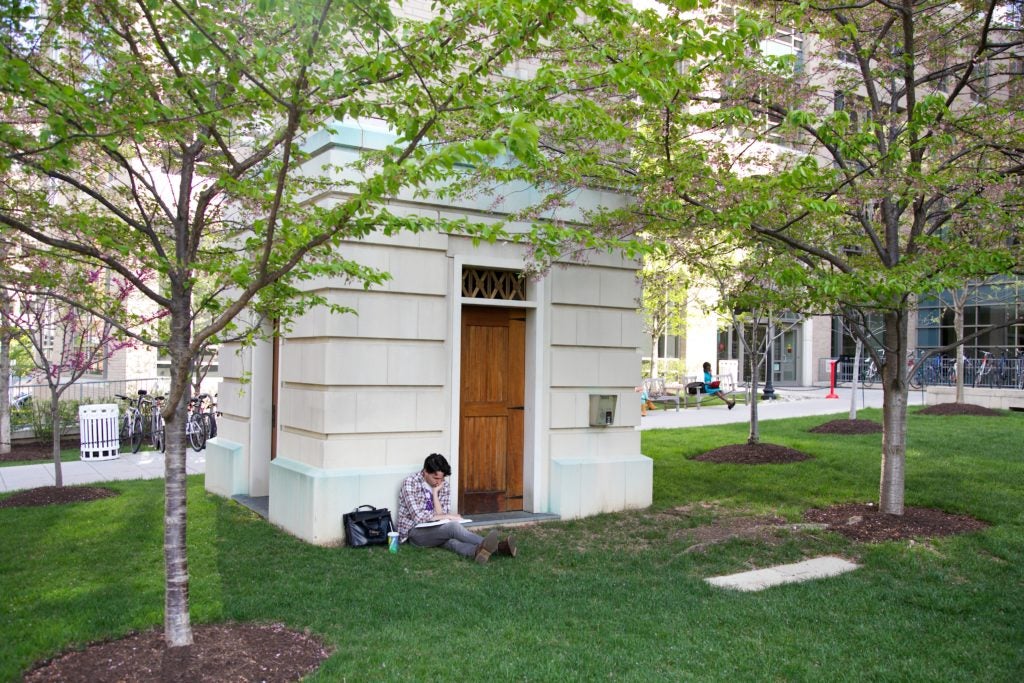 Student sitting on grass leaning against Clock Tower