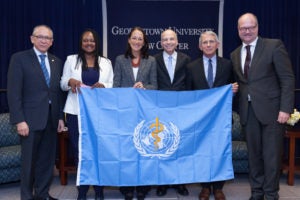 Professor Lawrence O. Gostin, center right, displays the World Health Organization flag with guests at the tenth anniversary celebration of the O’Neill Institute for National and Global Health Law at Georgetown Law.