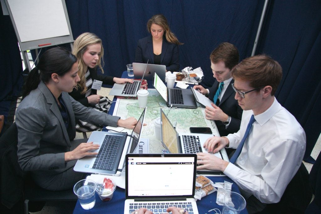 Students Huddle Around a Desk for the National Security Simulation