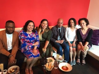 Six law school diversity and inclusion officers sit on couches and smile for the camera