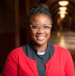 Rev. Ebony Grisom standing indoors and smiling at the camera