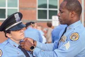 A New Orleans police officer affixes a pin to an officer's uniform after completing peer intervention training.