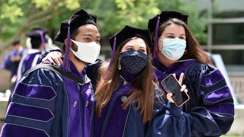 Graduates pose for photo with masks.