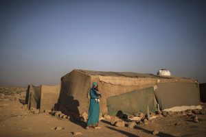 A Syrian refugee mother holds her daughter while standing outside her tent in a tented settlement in Jordan (photo by Muhammed Muheisen).