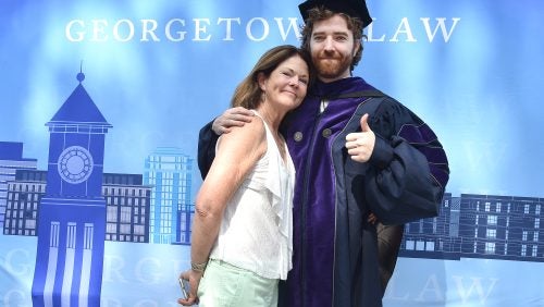 A woman and man pose for a photo on the Law Center campus