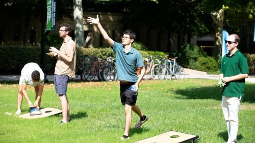Students playing cornhole on the campus green