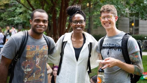 Three students posing together on the Law Center campus