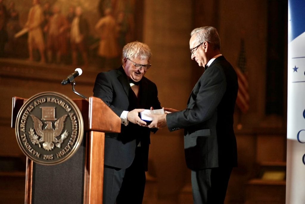 Two men at a podium, one handing the other an award