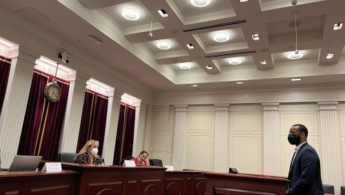 People seated at the bench in the moot courtroom and person standing at the podium in front of the bench. 