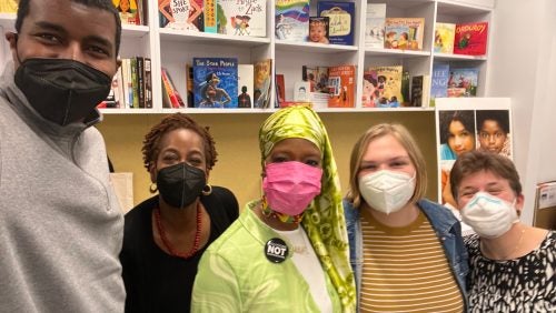 Five people standing together in front of a bookshelf.