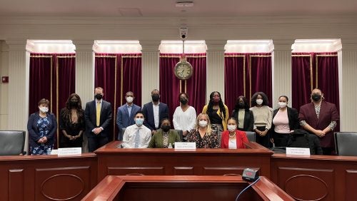 People seated and people standing behind them at the moot courtroom. 