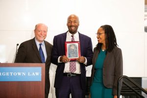 Dean William M. Treanor, left and Prof. Robin Lenhardt, right, present the Flegal Excellence in Teaching Award to Prof. Paul Butler, center