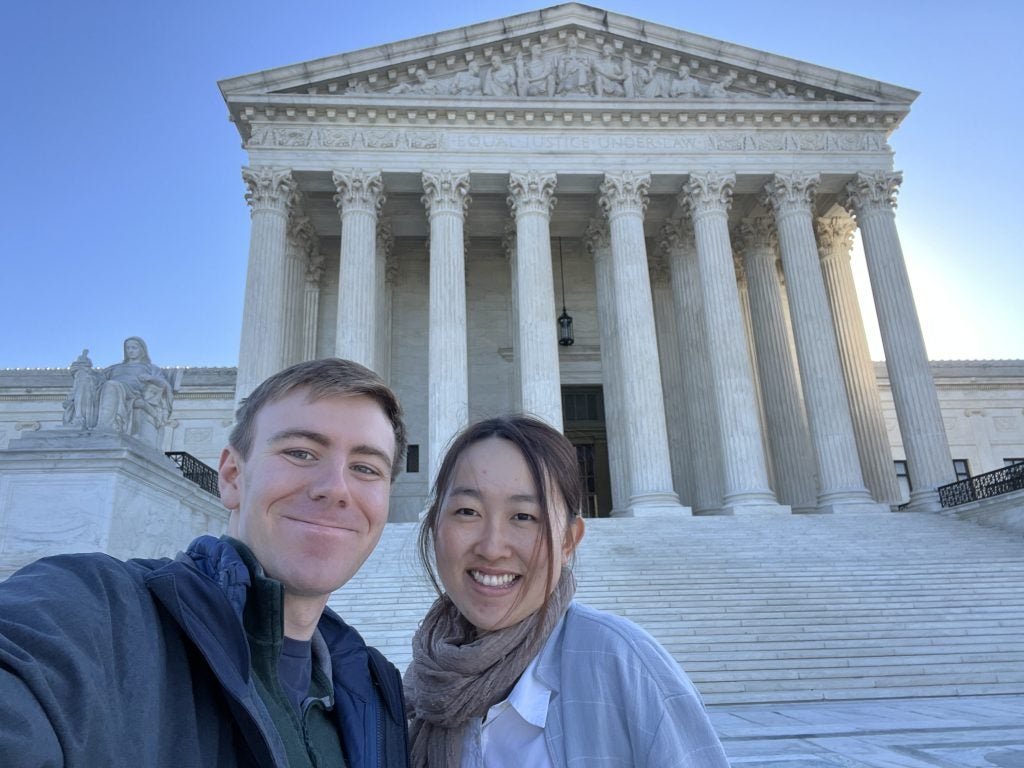 Two students smiling in front of the Supreme Court