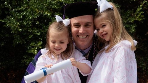 A graduating student with two young girls