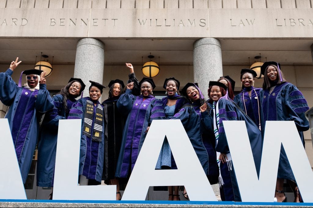 A group of Black women in graduation regalia, posing for a photo on the steps of the Georgetown Law library.