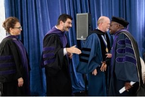 Members of the Georgetown Law faculty shaking hands with a graduate