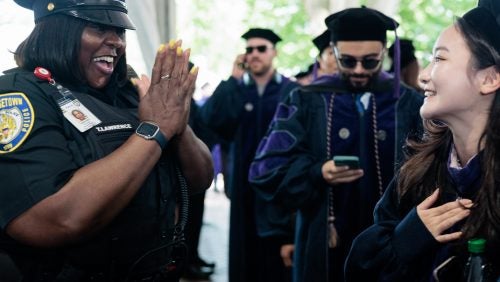A university security officer applauds graduating students